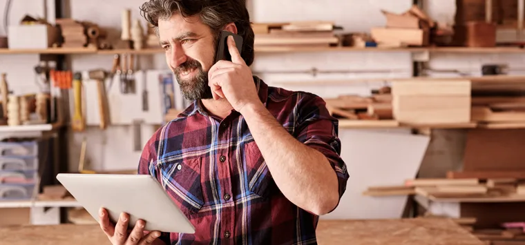 Handwerker telefoniert in seiner Werkstatt.