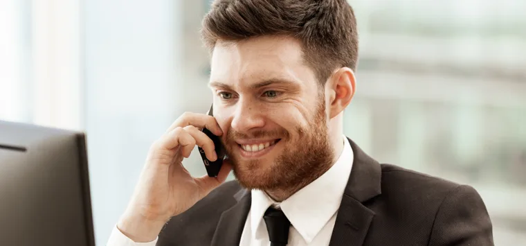 Mann im Anzug telefoniert mit dem Smartphone im Büro.